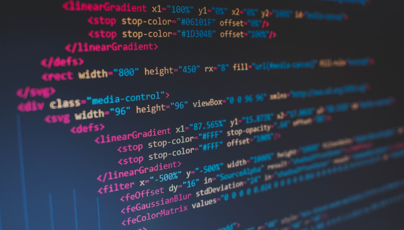 Developer writing code on a laptop with multiple monitors